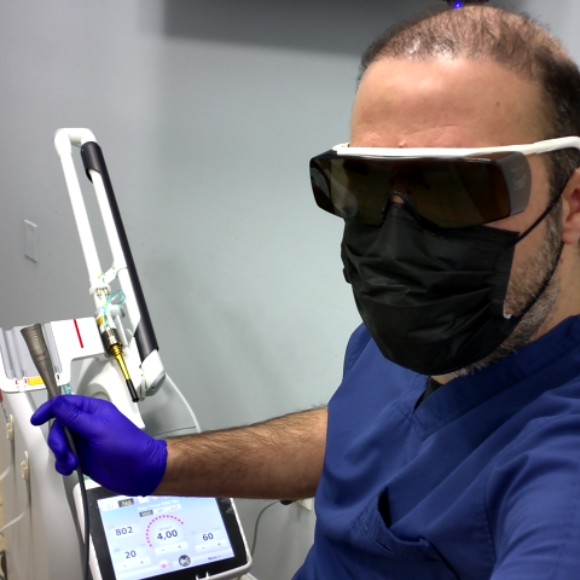 Dr. Firas Albadran holding the Genova handpiece for Photobiomodulation therapy at Richmond Dental Spa